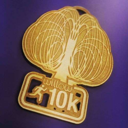 wooden medals. Intricate laser cut wooden medals manufactured in the UK. Purple background warm wooden medal. Willow 10K sports medals 2020.